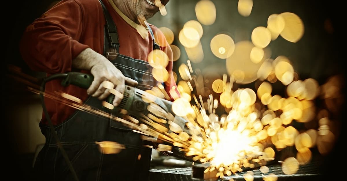 Industrial worker cutting and welding metal with many sharp sparks Man welding with sparks flying