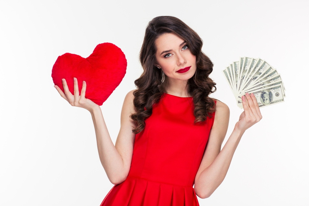 Portrait of a beautiful woman in red dress choosing between love or money isolated on a white background Woman weighing love and money options