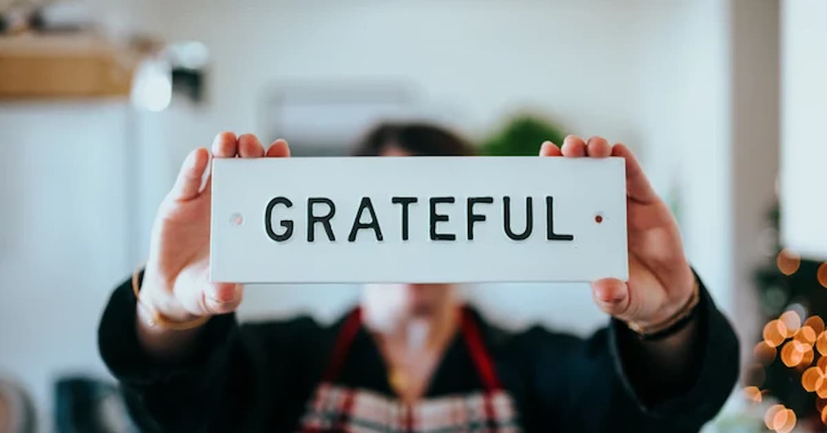 nathan-dumlao-fs_l0Xqlc90-unsplash Person holding a sign that says 'GRATEFUL'.